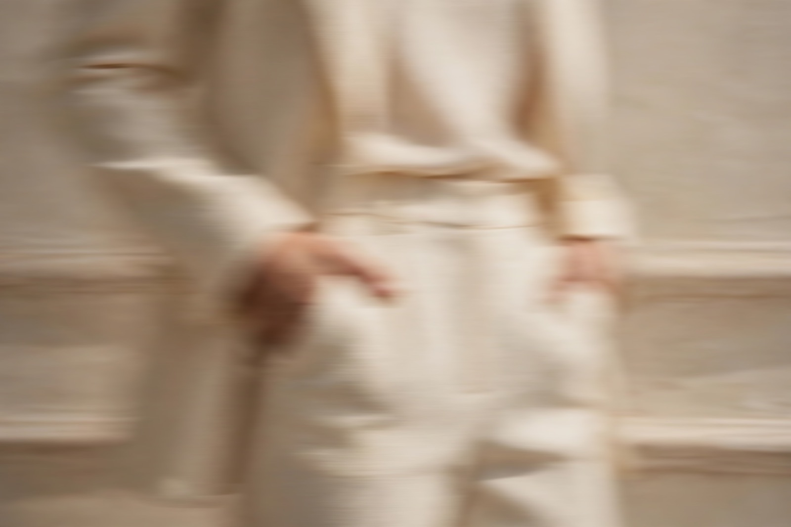 Hands in the pockets of a cream tailored suit